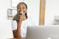 Young woman talking by phone while working on laptop at home