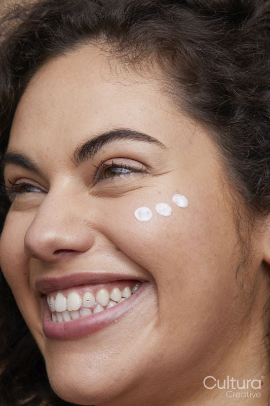 Close-up of young woman applying face cream