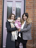 Two women standing at doorstep and holding baby