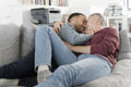 Smiling male couple cuddling on sofa at home