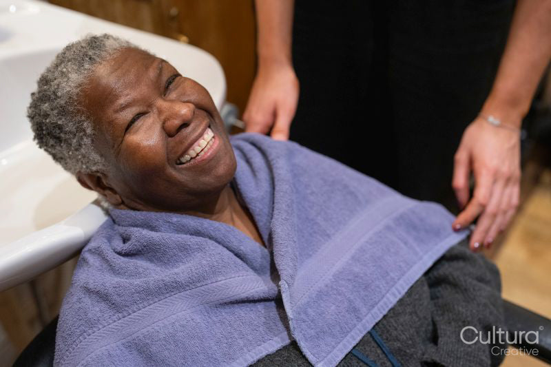 Smiling senior woman getting ready for hair wash in hair salon