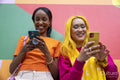 Young female friends using phones outdoors
