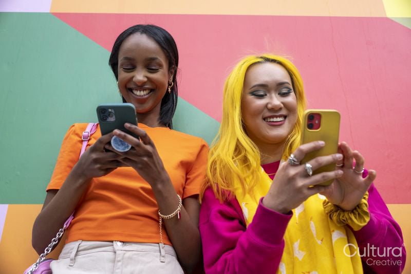 Young female friends using phones outdoors