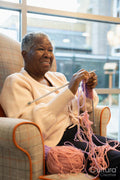 Smiling senior woman knitting in nursing home