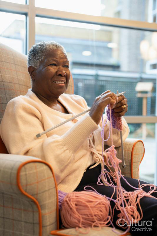 Smiling senior woman knitting in nursing home