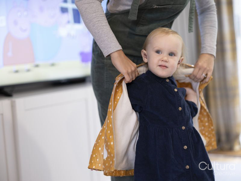 Mother helping daughter to put on raincoat