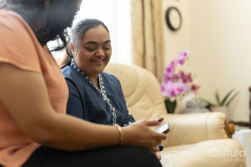 Woman with down syndrome daughter using smart phone at home