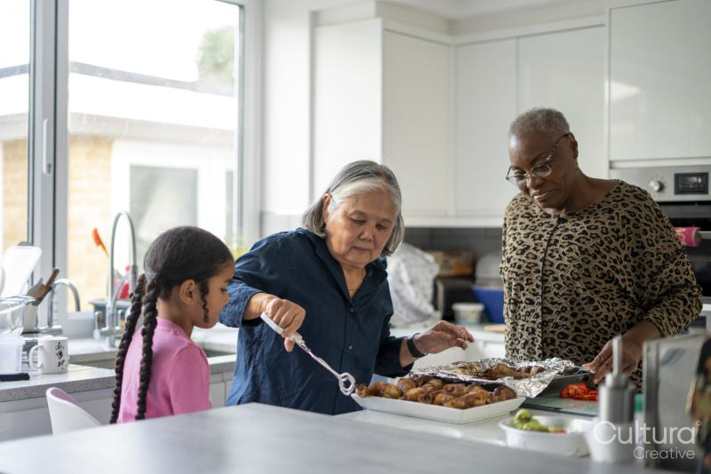 Two senior women and girl preparing meal in kitchen