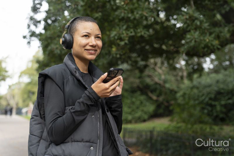Smiling woman with headphones and smart phone in park
