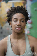 Portrait of serious woman looking at camera in front of climbing wall