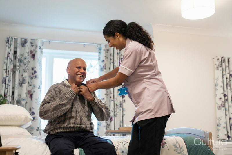 Nurse helping senior man to get dressed at nursing home