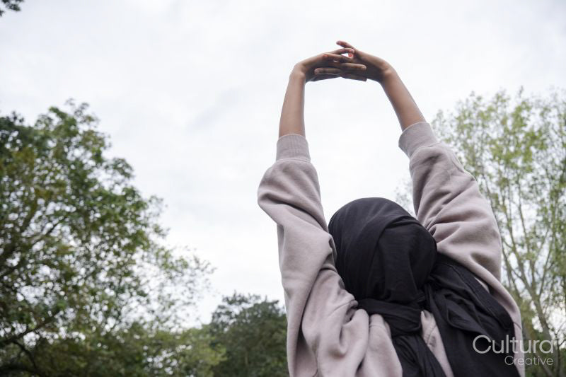 Rear view of woman in hijab stretching in park