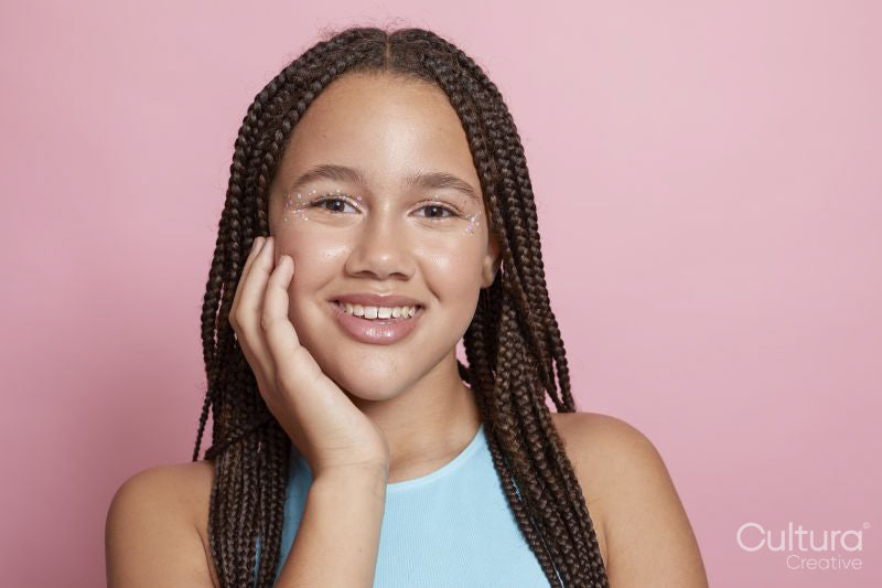 Studio portrait of smiling girl with braids and decorative stickers on face