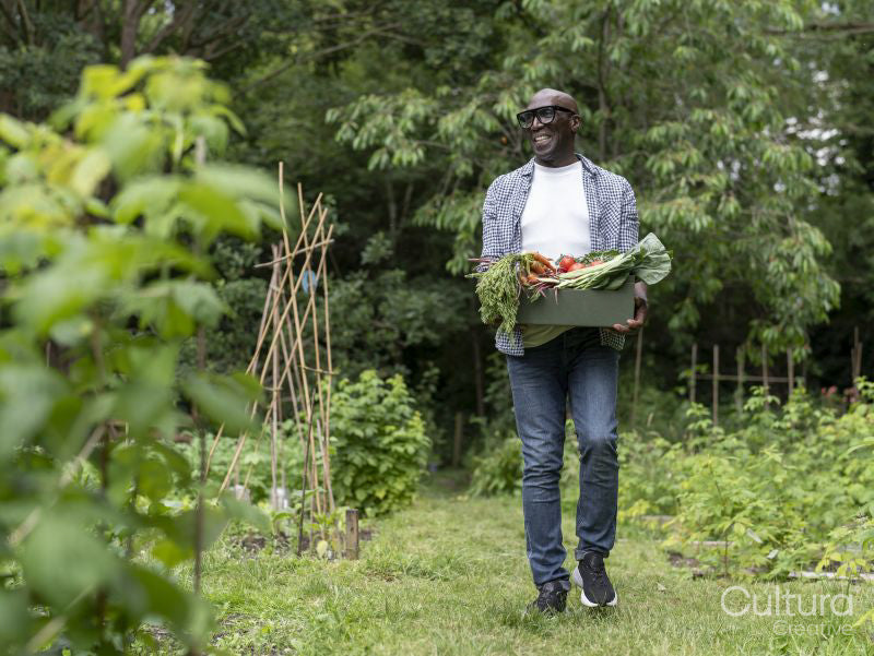 Smiling mature man holding vegetables from garden