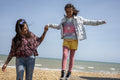 Smiling mother and daughter holding hands on beach