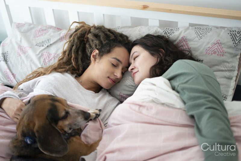 Two women and dog in bed