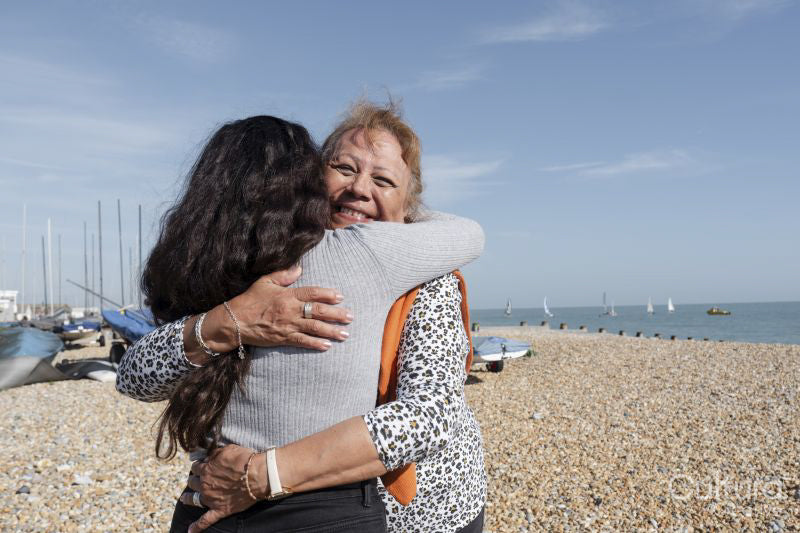 Mother and daughter embracing on beach on sunny day