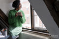 Smiling businesswoman holding cup of coffee while looking through window