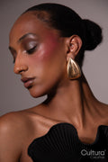 Woman in a black dress with gold earrings on a grey background