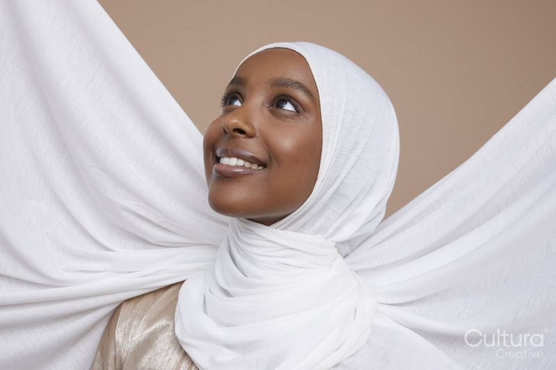 Studio shot of smiling young woman in white hijab