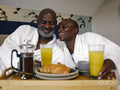 Smiling mature couple in bathrobes enjoying breakfast