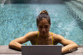 Woman using laptop while relaxing in swimming pool