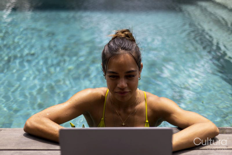 Woman using laptop while relaxing in swimming pool