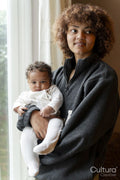 Mother holding baby daughter next to window