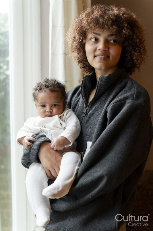 Mother holding baby daughter next to window