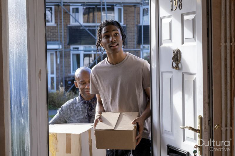 Father and son entering house with cardboard boxes