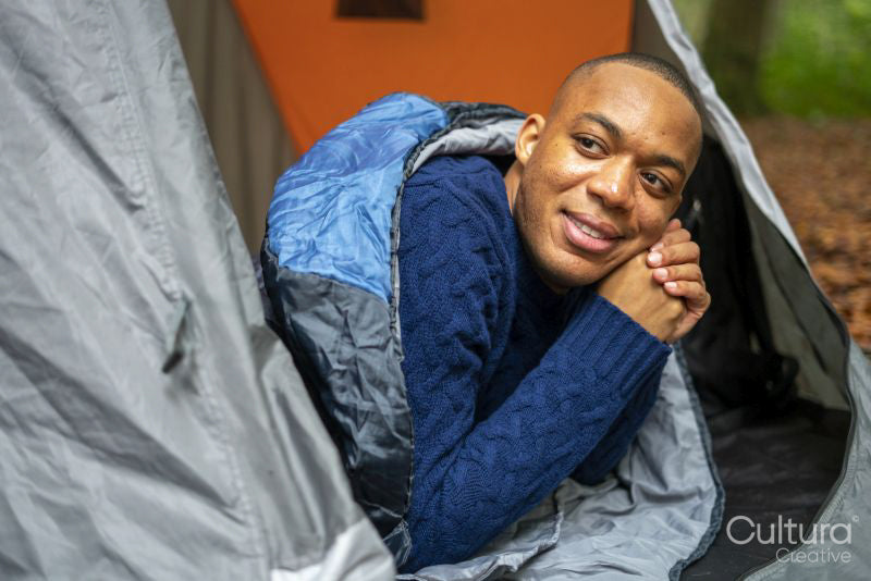 Man lying in open tent and looking outside