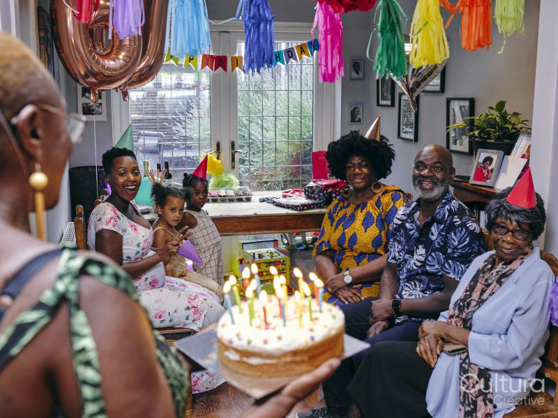 Multi-generation family celebrating birthday with birthday cake