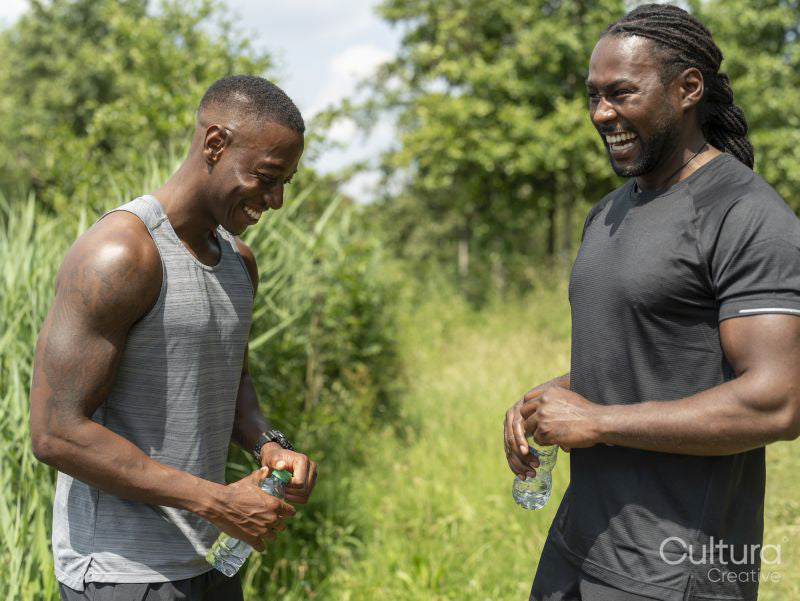 Two men drinking water after exercising outdoors