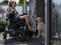 Woman in electric wheelchair relaxing on deck with dog
