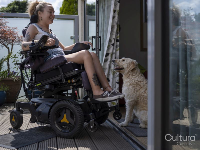 Woman in electric wheelchair relaxing on deck with dog