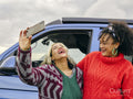 Female couple taking selfie in front of van