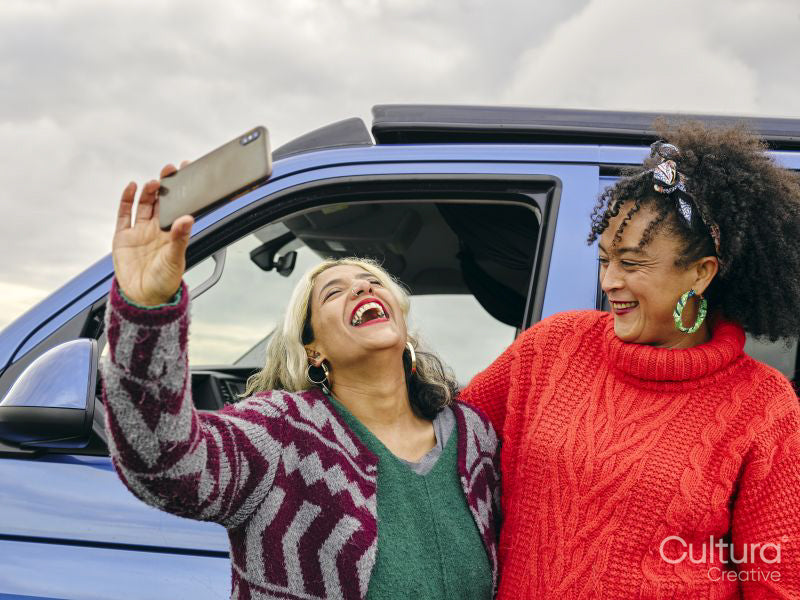 Female couple taking selfie in front of van