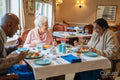 Group of seniors talking and dining at cafeteria in nursing home