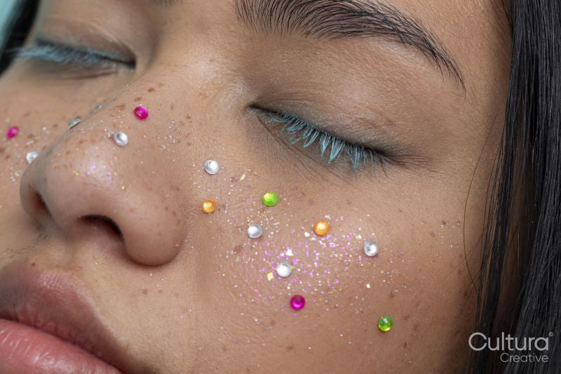 Close up of woman with closed eyes with colorful shiny freckles