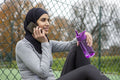 Woman in hijab talking on smart phone on basketball court
