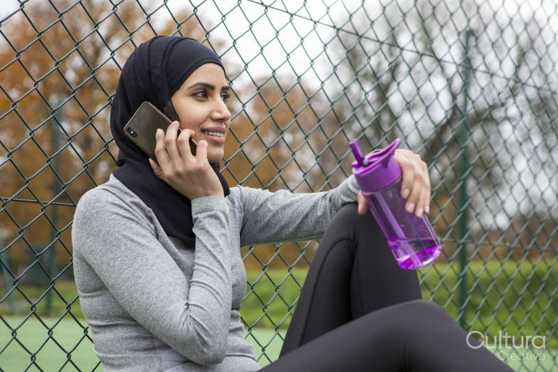 Woman in hijab talking on smart phone on basketball court