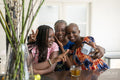 Smiling teenage girl with mother and grandmother taking selfie at table