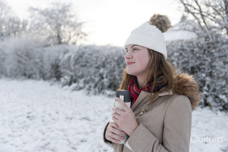 Smiling woman with bottle in winter landscape