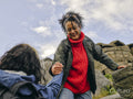 Woman helping fellow hiker climb rocky mountain
