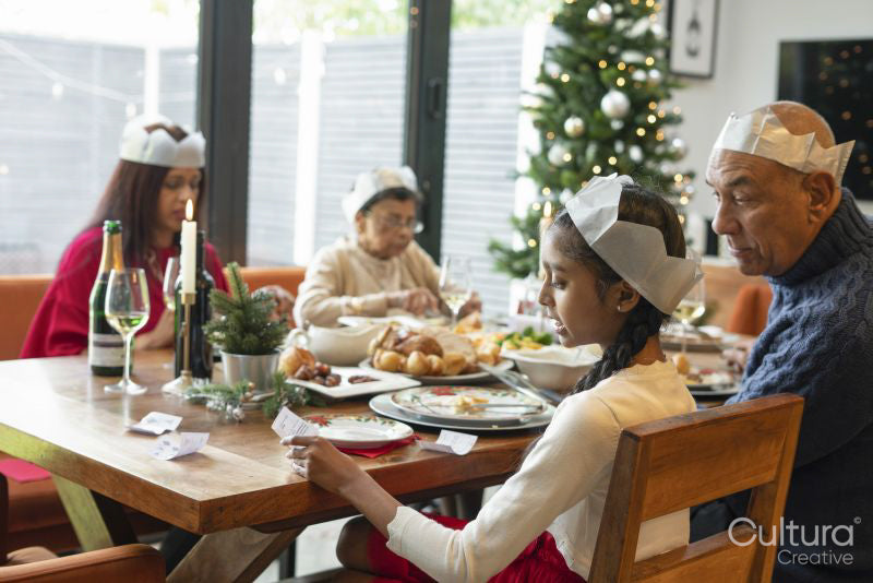 Family wearing paper crowns enjoying Christmas dinner
