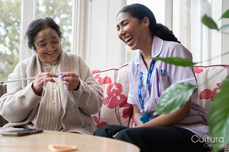 Senior woman knitting and talking to care giver in nursing home