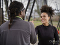 Smiling man and woman in sports clothing arm wrestling outdoors
