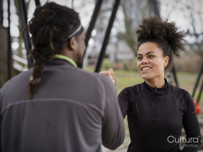 Smiling man and woman in sports clothing arm wrestling outdoors