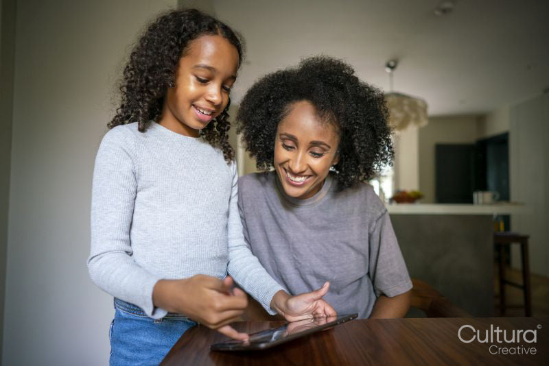 Girl showing digital tablet to mother at home