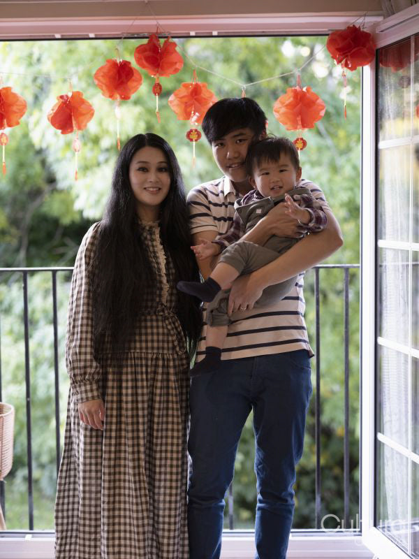 Portrait of family standing next to window with traditional Chinese decorations